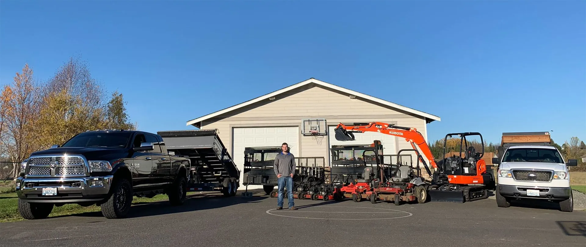 elite landscape owner standing in front of heavy equipment